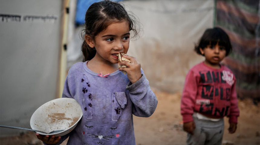 Striscia di Gaza - Israa, una bambina di 3 anni, mangia un pezzo di pane mentre sta davanti alla tenda della sua famiglia nella città di Khan Younis